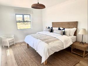 a bedroom with a large bed and a window at White Wicker House in Langebaan