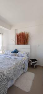 een slaapkamer met een bed met een witte muur bij Chillis Penthouse in Porlamar