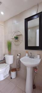 een badkamer met een wastafel, een toilet en een spiegel bij Chillis Penthouse in Porlamar