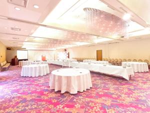 Un salón de banquetes con mesas y sillas blancas sobre una alfombra colorida. en 下関大坂屋ホテル, en Shimonoseki