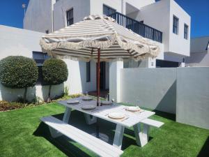 a picnic table with an umbrella on a lawn at White Wicker House in Langebaan