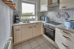 a kitchen with white cabinets and a sink and a window at Refugium - Möhneseeblick in Möhnesee