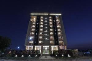 Un edificio alto con luces en la parte superior por la noche. en Empyrean Resort, en Gandhinagar