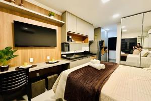 een slaapkamer met een bed en een keuken met een tv bij Studio Safira | Sofisticação e Harmonia in Uberlândia