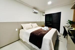 een slaapkamer met een bed met een handdoek erop bij Studio Safira | Sofisticação e Harmonia in Uberlândia +31 foto's