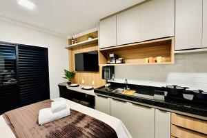 een keuken met witte kasten en een houten tafel bij Studio Safira | Sofisticação e Harmonia in Uberlândia