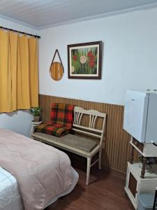 a bedroom with a bed and a chair and a television at Dexa Hospedagem in Ouro Preto