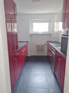 una cocina vacía con armarios rojos y una ventana en Zimmer-Leutkirch, en Leutkirch im Allgäu