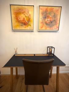 a black desk with two paintings on a wall at Atelier Lomani in Vienna