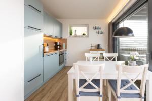a kitchen with white cabinets and a white table and chairs at Fewo Wellenklang Hainer See bei Leipzig in Neukieritzsch
