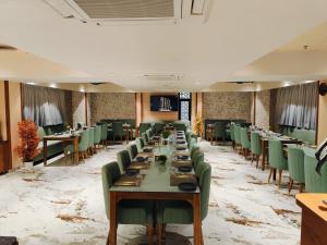 Un largo comedor con mesas y sillas verdes. en Empyrean Resort, en Gandhinagar