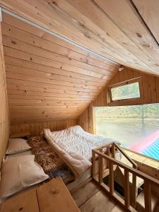 a bed in a wooden room with a window at Shiva Valley Riverside in Jibhi