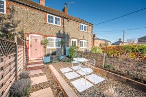 een bakstenen huis met een tafel en een roze deur bij Pink Cottage in Leiston