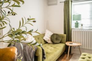 een woonkamer met een groene bank en een plant bij Pink Cottage in Leiston