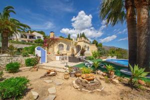een huis met een zwembad en een tuin met palmbomen bij Villa Sabine - PlusHolidays in Calpe