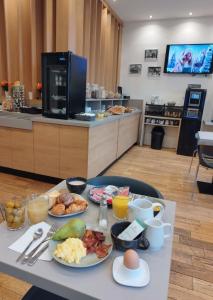 a table with plates of breakfast food on it at Hôtel Le Mondon Metz in Metz
