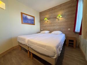 a bedroom with a bed with a wooden wall at Résidence Christiana 406 Clés Blanches Courchevel in La Tania