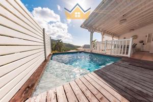 a house with a swimming pool and a wooden deck at La Villa du soleil in Les Trois-Îlets