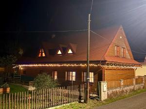a wooden house with lights on the front of it at Chata Bella in Mýto pod Ďumbierom