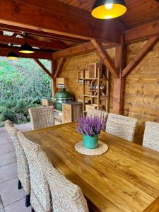 a wooden table with chairs and a vase of purple flowers at Chata Bella in Mýto pod Ďumbierom
