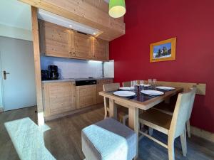 谷雪维尔Résidence Christiana 408 Clés Blanches Courchevel的厨房配有木桌和红色的墙壁
