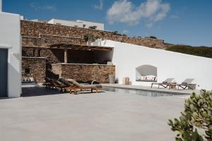a patio with lounge chairs next to a brick wall at Villa Anamnesia, Stelida Naxos in Stelida