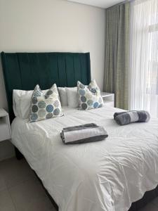 a large bed with a green headboard and pillows on it at Flat 4 Block 12 Bellamare in Port Elizabeth