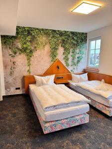 two beds in a room with a wall with ivy at Hotel Garni Eschenbach in Hildburghausen
