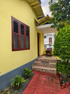 Una casa amarilla con escaleras y un banco encima. en Wild Forest Inn Thekkady, en Thekkady