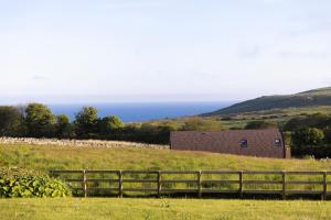 a fence in a field with the ocean in the background at Byrnside Lodge in Latheron