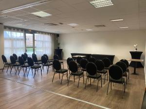 una grande stanza con sedie e un podio di Hôtel Restaurant Les Fontaines a Lanvollon