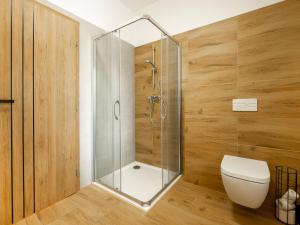 a bathroom with a shower with a toilet and wooden walls at Apartmány Bližší Lhota in Bližší Lhota