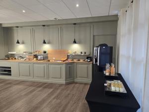 a large kitchen with a counter and a refrigerator at Logis Hôtel Restaurant Les Fontaines in Lanvollon