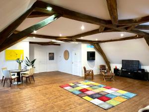 een woonkamer met een tafel en stoelen en een tapijt bij KVS Concept Hébergement haut de gamme près du Circuit des 24 Heures du in Écommoy