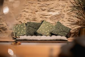a couch with pillows on a table in front of a stone wall at Love Room Vendée avec JACUZZI privatif in Nesmy +5 photos