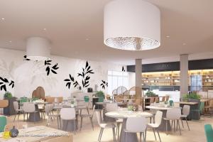 ein Restaurant mit Tischen und Stühlen und einem großen Kronleuchter in der Unterkunft Hotel Garden Istra Plava Laguna in Umag