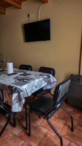 Una mesa de comedor con cuatro sillas y un televisor. en Cabañas Matices, en El Calafate
