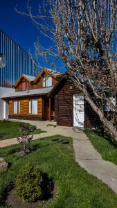 una casa de madera con un árbol delante en Cabañas Matices, en El Calafate