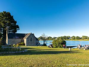 a group of people standing around a church next to a lake at Saint-Philibert: Appart 2 pièces, 53m², terrasse, parking, 4 pers - FR-1-477-249 in Saint-Philibert