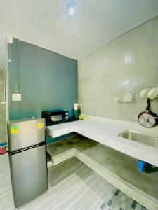 Una pequeña cocina con nevera y fregadero. en Baan Amila, en Phra Ae beach