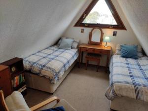 een zolderslaapkamer met twee bedden en een raam bij Chalet Seventyfour in Deal