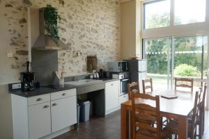 a kitchen with a sink and a table with chairs at Gîte les charrières in Pouzauges