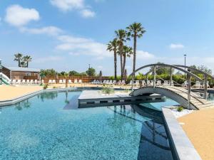 einen Pool mit einer Brücke und Palmen in der Unterkunft Blue Camargue - Le Grau du Roi in Le Grau-du-Roi + 19 Fotos