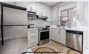 een keuken met witte kasten en roestvrijstalen apparaten bij Comfortable 4B Unit-Close to City Attractions in Montreal
