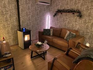 ein Wohnzimmer mit einem Sofa und einem Tisch mit einem Kamin in der Unterkunft Luxury bungalow Woldzicht in Appelscha