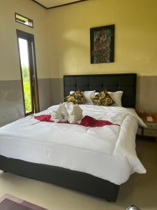 ein Bett mit weißen Laken und Kissen in einem Schlafzimmer in der Unterkunft Wayan Bola Homestay in Sidemen