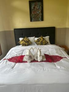 ein weißes Bett mit zwei ausgestopften Tieren drauf in der Unterkunft Wayan Bola Homestay in Sidemen
