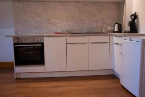 Una cocina con gabinetes blancos y un fregadero. en Fewo Kupferschmid, en Sasbachwalden