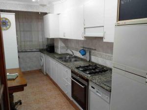 una cucina con mobili bianchi, un lavello e una stufa di Beach apartment a Valencia