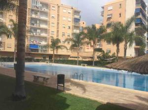 una piscina con panchina e alcuni edifici di Beach apartment a Valencia
